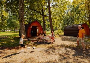 een gezin dat met een voetbal speelt voor een tent bij AZUR Waldcamping Auwaldsee in Ingolstadt