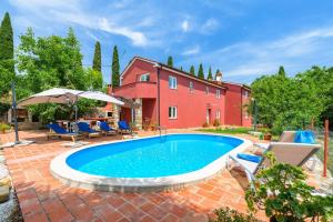 a pool in front of a house with chairs and an umbrella at Villa Mamma Mia in Oprtalj