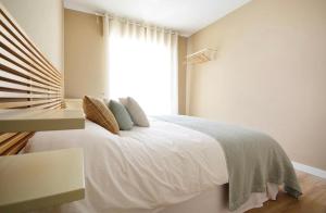 a bedroom with a large white bed with a window at La Casa De Roma in Cambados