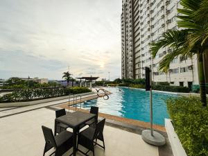 a swimming pool with a table and chairs next to a building at Heart of CDO Cozy Condo Wi-fi Netflix in Cagayan de Oro