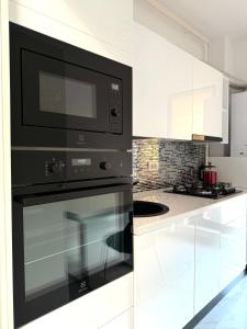 a kitchen with a black microwave and white cabinets at Studio Plaza Faza 2 in Militari