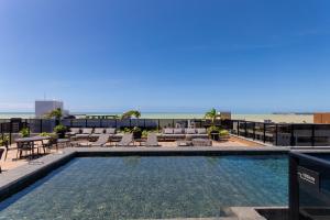 a swimming pool with lounge chairs and the beach at Way Tambaú #O7 - Studio Triplo deluxe by Carpediem in Tambaú