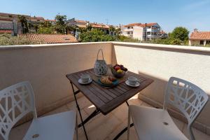 a small table with a bowl of fruit on a balcony at Extravagantes Apartment nur 100 Meter zum Strand mit Salzwasserpool und Jacuzzi in Funtana