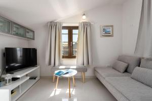 a living room with a couch and a tv at Traumhaftes Apartment nur 100 Meter zum Strand mit Jacuzzi, Meerblick, Salzwasserpool in Funtana