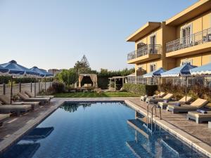 a hotel with a pool with lounge chairs and a building at Memories Apartments - Explore & Recharge in Laganas
