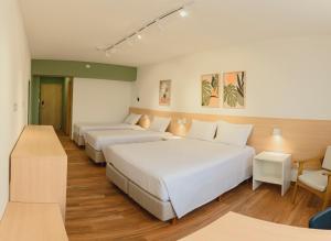 コチアにあるBleev Thermas da Mata - Cotia próximo ao Animália Parkのベッド3台とテーブルがあるホテルの部屋