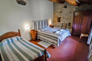 a bedroom with two beds and a stone wall at Agriturismo La Fattoria in Monte Santa Maria Tiberina