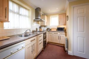 a kitchen with white cabinets and a sink and a window at Garden Cottage in Great Yarmouth