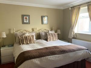 a bedroom with a bed with pillows and a window at Garden Cottage in Great Yarmouth