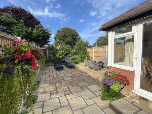 a patio with chairs and flowers in a yard at Garden Cottage in Great Yarmouth +2 photos
