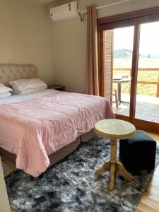 a bedroom with a bed and a table and a window at Vale de cambara III in Cambará
