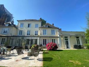 a large white house with chairs in the yard at Hôtel particulier Au pied de la cathédrale in Beauvais
