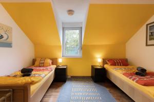 Dos camas en una habitación con paredes amarillas. en Tifra-living, en Hardenberg