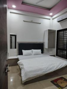a bedroom with a large bed with white sheets at Satyabhama Homestay-Opel-2 BHK Apartment in Indore