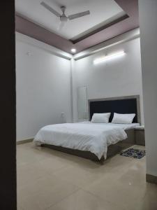 a white bedroom with a bed with a ceiling at Satyabhama Homestay-Opel-2 BHK Apartment in Indore