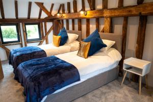 two beds in a room with wooden beams at The Barn at Chart Hills in Biddenden