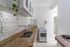 eine Küche mit Spüle und Herd in der Unterkunft Apto Aconchegante a 350m da Praia do Forte ECF0306 in Škorak