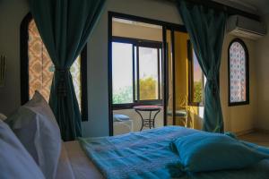 a bedroom with a bed and a window and a table at Weedan Hotel & Spa Marrakech in Oulad Snaguia