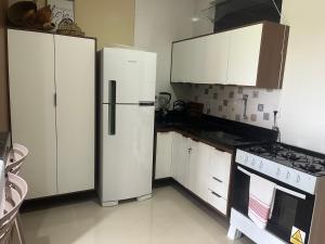 a kitchen with white cabinets and a refrigerator at Flat Ilha Bela 22525 in Alter do Chao