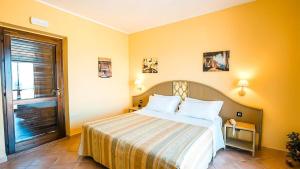a bedroom with a large bed with yellow walls at Villaggio Porto Rhoca in Squillace