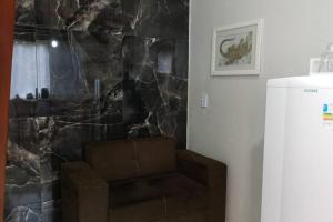 a living room with a brown couch and a stone wall at Kitnet MiniHouse do Alto in Lençóis