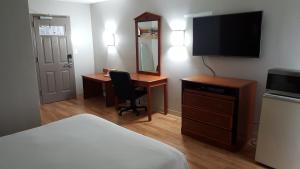 a hotel room with a bed and a desk and a television at Crystal Inn - Neptune in Neptune City