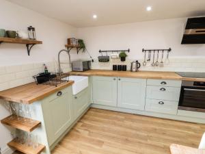 une cuisine avec des armoires blanches et des comptoirs en bois dans l'établissement Holborn Cottage, Blencathra Street, à Keswick