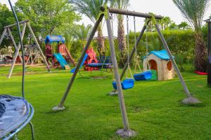 a park with a bunch of swings in the grass at Weedan Hotel & Spa Marrakech in Oulad Snaguia