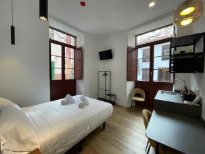 1 dormitorio con cama blanca, escritorio y ventanas en Hotelito Boutique Tenerife Guimerá, en Santa Cruz de Tenerife