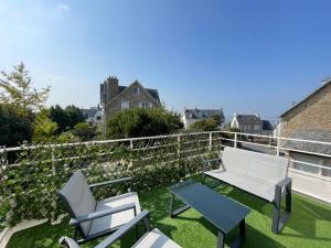 a patio with chairs and a bench on a balcony at Joli appartement avec balcon au pieds des commences et des plages in Carantec +9 photos