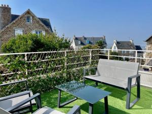 a patio with a white chair and a table at Joli appartement avec balcon au pieds des commences et des plages in Carantec