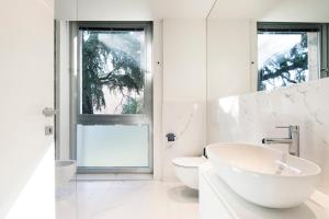 a white bathroom with a sink and a toilet at RELSTAY - Montenapoleone in Milan +163 photos