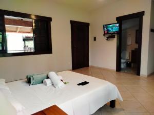 a white bed in a room with a television at Mansão Sunset Beach House in São Sebastião