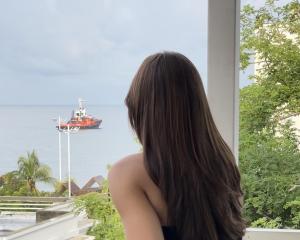 Eine Frau schaut aus einem Fenster auf ein Schiff in der Unterkunft MuchoSur Santa Marta in Santa Marta + 58 Fotos