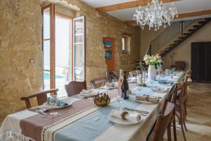 a dining room with a long table with chairs and a chandelier at Maison Flamant in Saint-Geniès-de-Fontedit
