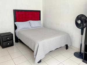 a bedroom with a bed with a red headboard and a fan at Departamento 3Hab 7min del Centro in Tehuacán