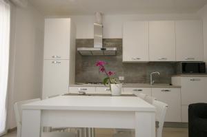a white kitchen with a white table and white cabinets at Residenza Adua Evangelisti Casa in Bellaria-Igea Marina