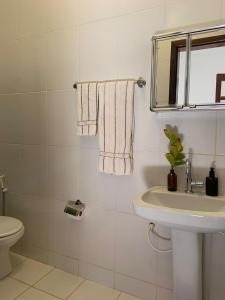 een badkamer met een wastafel en een spiegel en een toilet bij Suíte Pitangueira - Hospedaria Sonho De Infância in Mato Verde