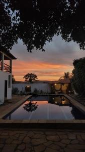 een zwembad voor een huis met een zonsondergang bij Suíte Pitangueira - Hospedaria Sonho De Infância in Mato Verde