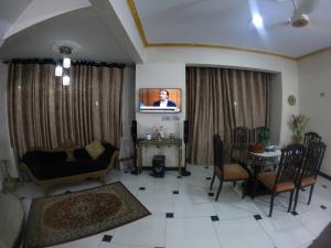 a living room with a tv and a table and chairs at Kashmir Cottage Muzaffarabad in Muzaffarabad