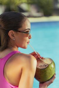 a woman drinking a drink with a straw in a coconut at Ritz Lagoa da Anta Hotel & SPA in Maceió +70 photos