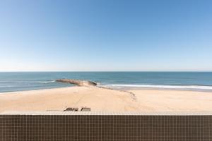 a view of a beach with two chairs on the sand at Exe Praia Golfe in Espinho +88 photos