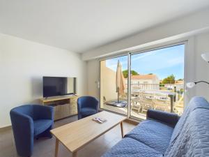 a living room with a couch and a tv and a balcony at Appart pour 4 centre ville - proche de la gare in Saint-Hilaire-de-Riez