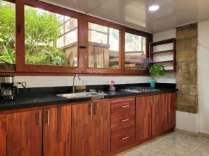 une cuisine avec des armoires en bois et un évier dans l'établissement La Pascana Ecolodge APTO BARRANQUERO frente al parque Arví Entorno natural excepcional, reserva natural, áreas protegidas, conexión con la naturaleza y avistamiento de aves a 3km del metrocable Guarne, à Guarne 10 autres photos