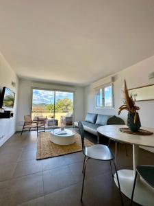 Una sala de estar con un sofá, una mesa y sillas. en ALTO DI PINARELLO, en Sainte-Lucie de Porto-Vecchio