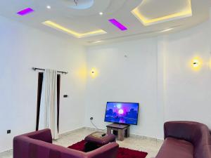 a living room with two couches and a flat screen tv at Les Résidences Terre Royale in Sokouhoué