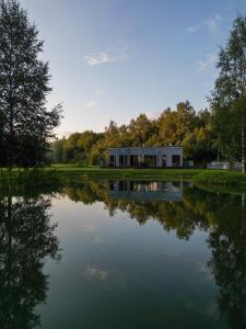 a house sitting on top of a lake at Dabas Osta in Jūdaži