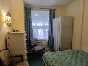 a bedroom with a bed and a window and a chair at Charming Garden Flat in Kent
