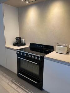 a kitchen with a black stove and white counters at Maison Olive in Torhout +28 photos