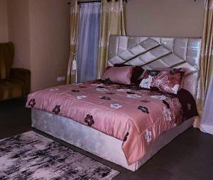 a bedroom with a large bed with a pink comforter at Lekki Apartment in Lekki